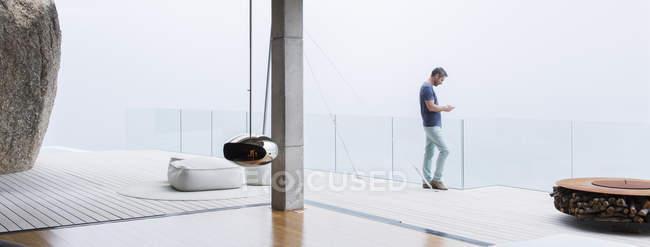 Людина використовує мобільний телефон на балконі сучасного будинку — стокове фото