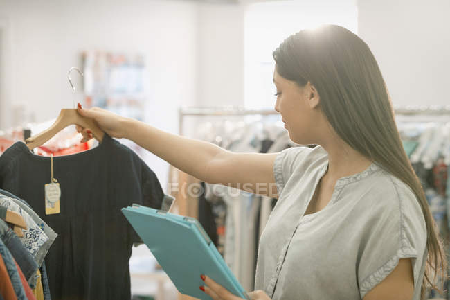 Comprador de moda con tableta digital mirando camisa - foto de stock