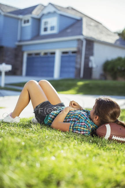 Menina que coloca no futebol na grama fora da casa — Fotografia de Stock