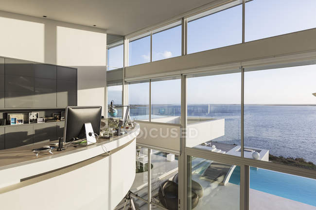 Moderna casa de luxo vitrine interior home office com vista para o mar ensolarada — Fotografia de Stock