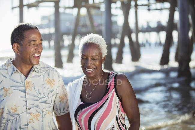 Senior couple on beach near pier — Stock Photo