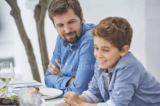 Отец и сын обедают за обеденным столом во дворе — стоковое фото