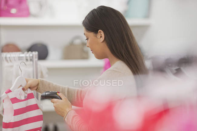 Clothing shop owner scanning clothing doing inventory — Stock Photo