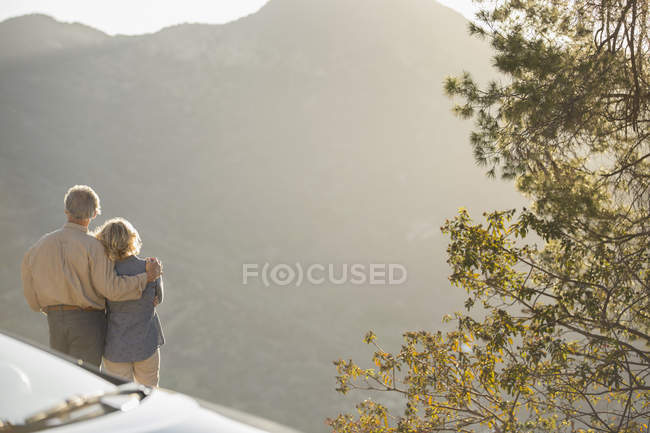 Seniorenpaar schaut sich Bergblick vor Auto an — Stockfoto