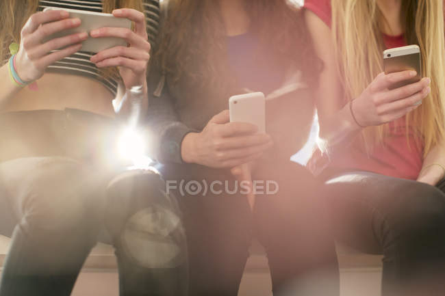 Teenager-Mädchen, die hintereinander mit Mobiltelefonen SMS schreiben — Stockfoto