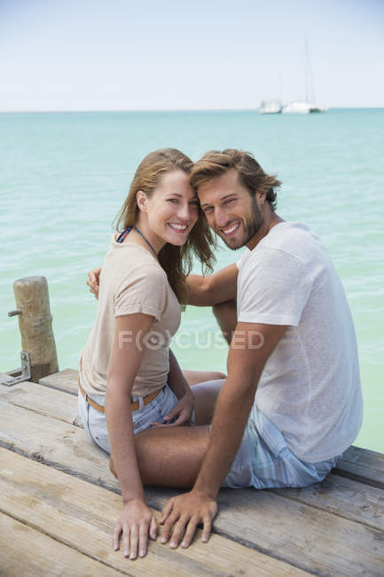 Пара сидить на краю дерев'яного причалу разом — стокове фото