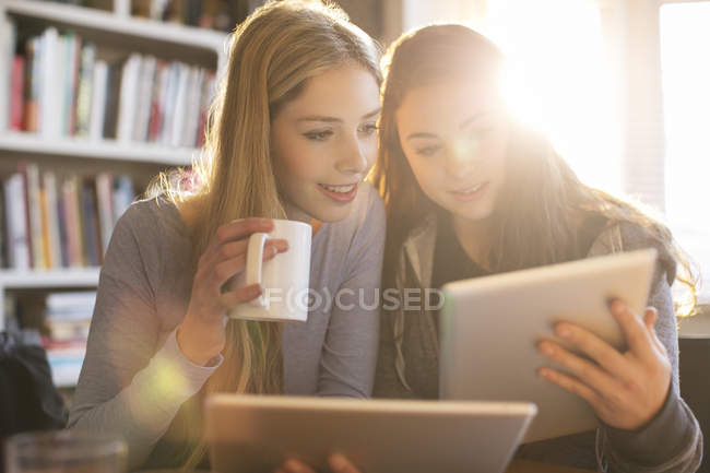 Les adolescentes boivent du café et utilisent des tablettes numériques — Photo de stock