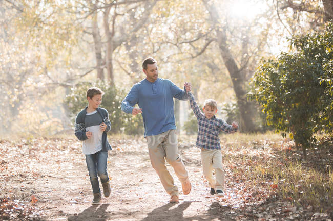 Playful father and sons running on trail in woods — Stock Photo