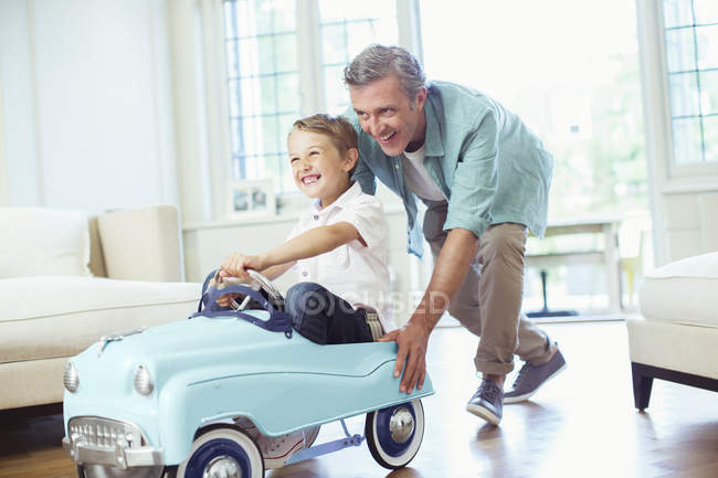 Padre spingendo figlio in macchina giocattolo — Foto stock