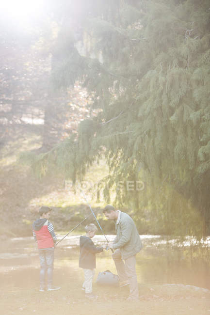 Father and sons preparing fishing rods in woods — Stock Photo