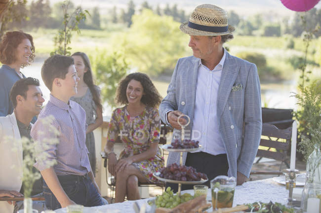 Feliz familia moderna hablando cerca de mesa de picnic - foto de stock