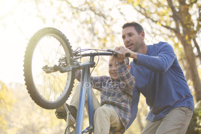 Pai ensinando filho wheelie na bicicleta — Fotografia de Stock