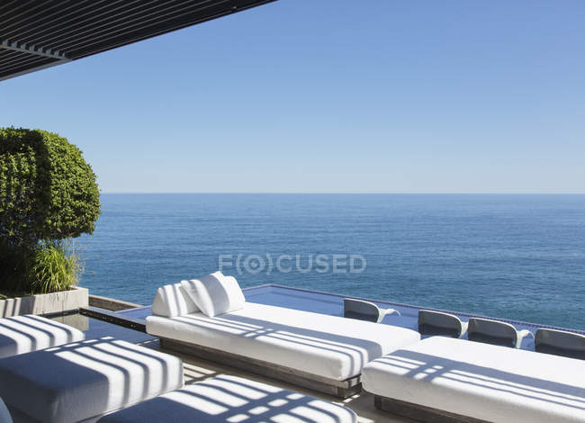 Sofas and infinity pool overlooking ocean — Stock Photo