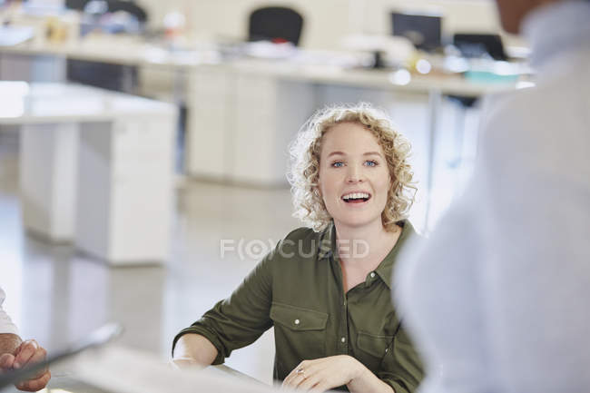 Улыбающаяся деловая женщина слушает на встрече в современном офисе — стоковое фото