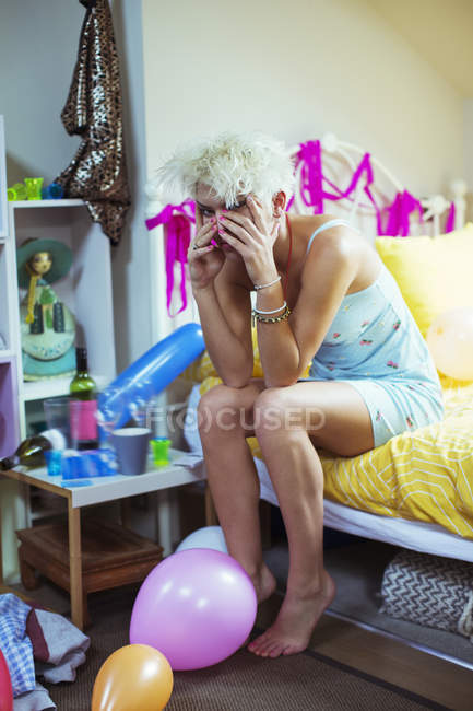 Жінка потирає обличчя на ліжку вранці після вечірки — стокове фото