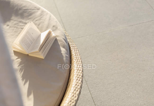 Open book on sunny lounge chair — Stock Photo