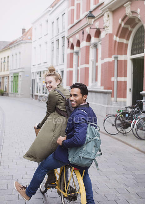 Retrato sorrindo jovem e mulher andando de bicicleta na rua da cidade — Fotografia de Stock