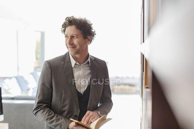 Smiling businessman reading book and looking away — Stock Photo