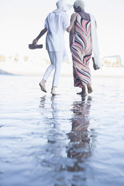 Вид ззаду жінки, що йдуть босоніж на пляжі — стокове фото
