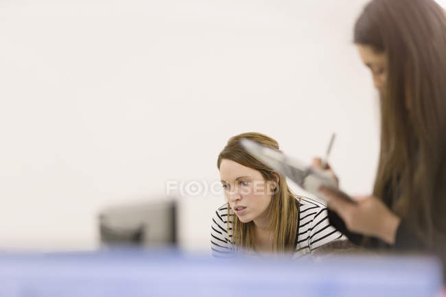 Businesswomen with clipboard working at computer — Stock Photo