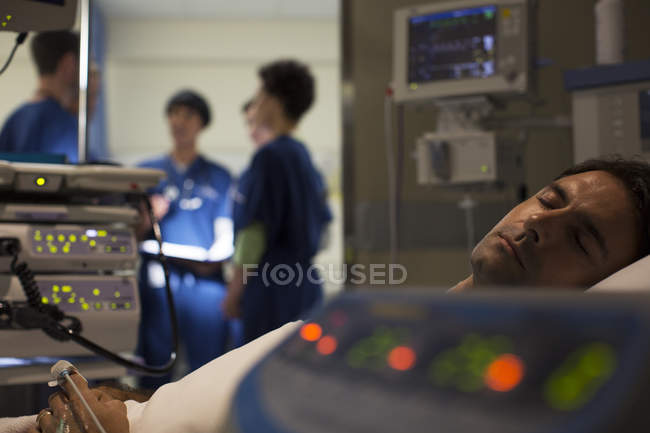 Пациент, окруженный оборудованием для медицинского мониторинга в отделении интенсивной терапии — стоковое фото