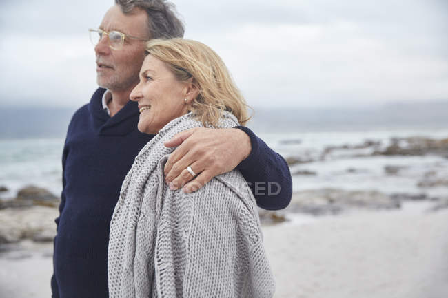 Affectueux couple de personnes âgées câlins sur la plage d'hiver — Photo de stock
