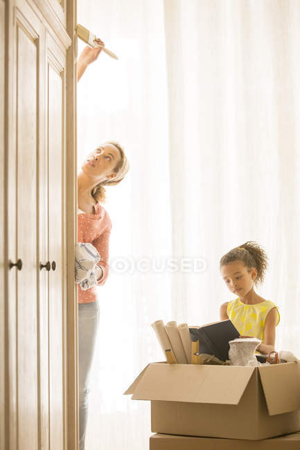 Mother painting wardrobe with daughter reading — Stock Photo