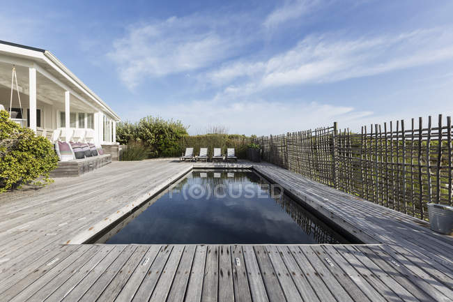 Tranquille maison vitrine piscine entourée d'une terrasse en bois — Photo de stock