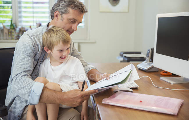 Син сидять на колінах батька робочий — стокове фото