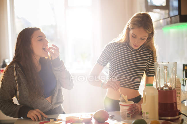 Ragazze adolescenti che fanno frullato in cucina soleggiata — Foto stock