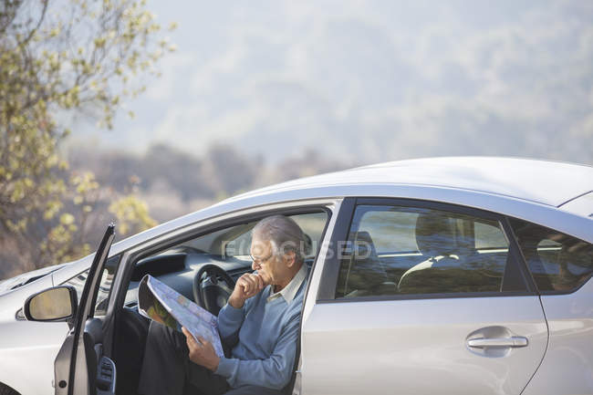 Senior Mann im Auto schaut auf Karte — Stockfoto