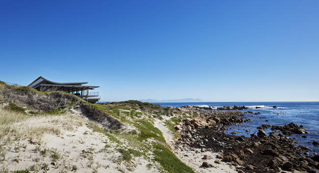Дом с видом на океан под солнечным голубым небом — стоковое фото