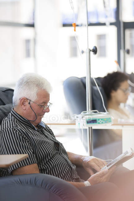 Man reading magazine, undergoing medical treatment in outpatient clinic — Stock Photo