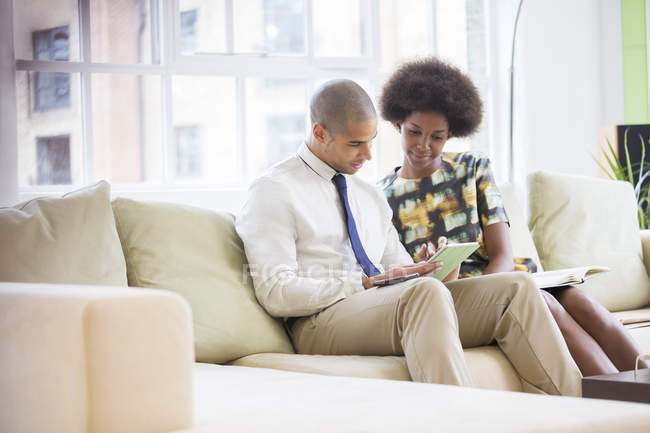 Business people using digital tablet on sofa — Stock Photo