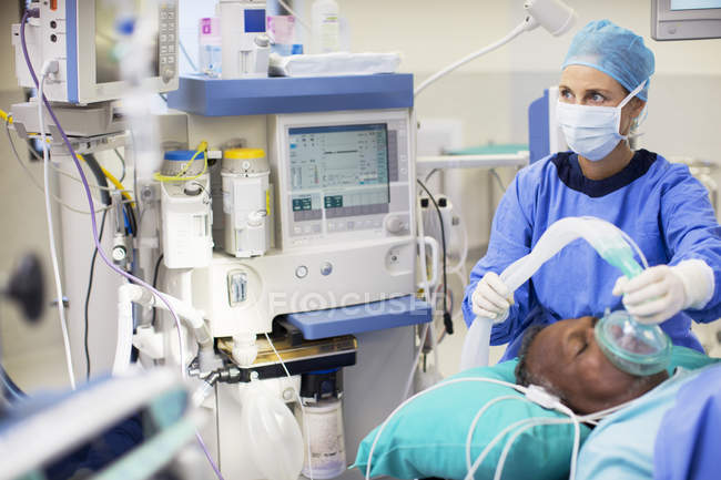 Doctora con ropa quirúrgica anestesiando a la paciente en quirófano - foto de stock