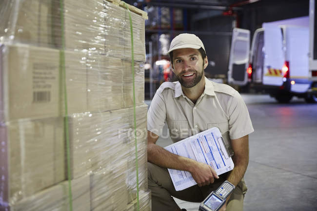 Portrait conducteur de camion confiant avec scanner à palette de boîtes en carton au quai de chargement de l'entrepôt de distribution — Photo de stock