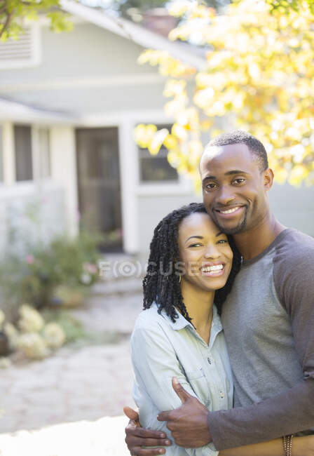 Portrait of smiling couple hugging outside house — Stock Photo