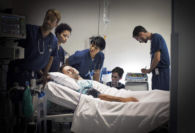 Grupo de médicos que atienden a pacientes en la sala de hospitalización - foto de stock