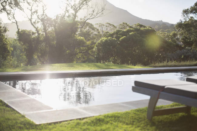 Cortile soleggiato con piscina sul giro e montagna sullo sfondo — Foto stock