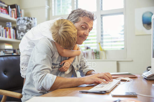 Junge umarmt arbeitenden Vater — Stockfoto