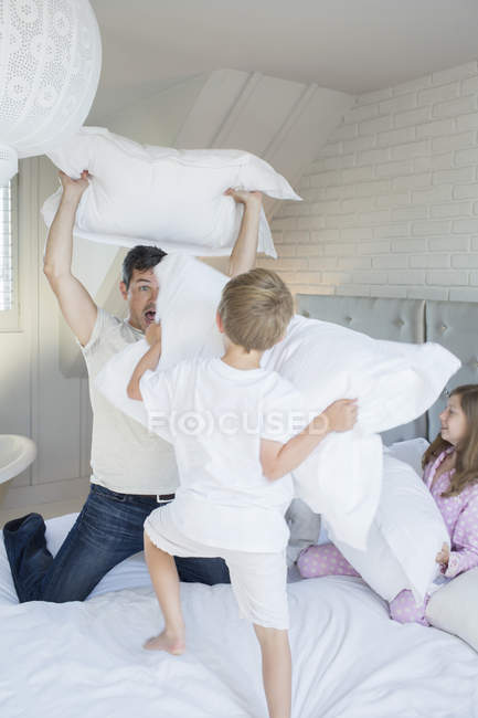 Padre e hijos teniendo pelea de almohadas - foto de stock