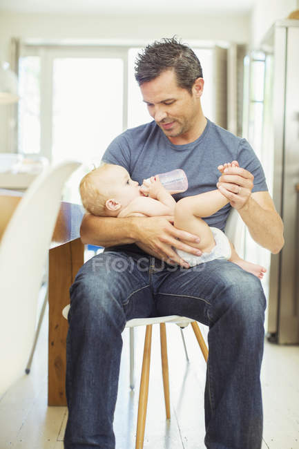 Father feeding baby in kitchen — Stock Photo