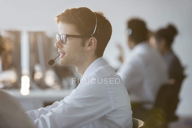 Homem de negócios usando fone de ouvido no escritório — Fotografia de Stock