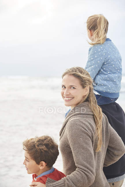 Портрет улыбающейся семьи, гуляющей по зимнему пляжу — стоковое фото