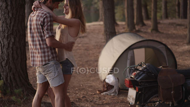 Прихильна молода пара обіймається зовні намету в лісі — стокове фото