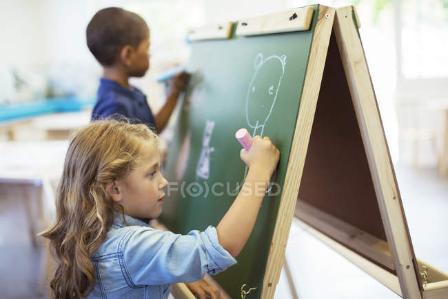 Students drawing on chalkboard in classroom — Stock Photo