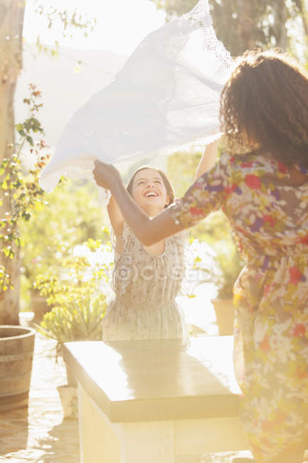 Mother and daughter laying table cloth on table — Stock Photo