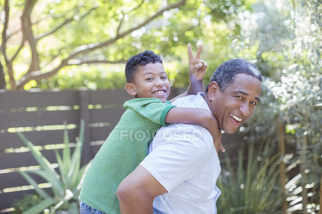Retrato de avô feliz piggybacking neto — Fotografia de Stock