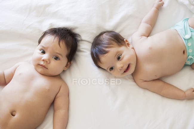 Twin adorable baby girls laying on bed — Stock Photo