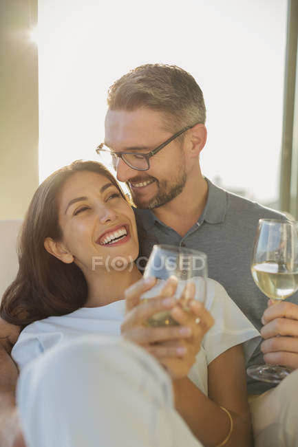 Pareja cariñosa sonriendo y bebiendo vino blanco - foto de stock